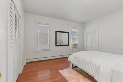 a white bedroom with a bed and two windows at Frog Hollow Red Door Retreat in Hartford
