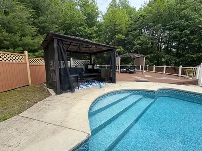 a gazebo next to a swimming pool at Cheerful 5-bedroom resort with heated pool in East Stroudsburg