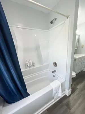 a white bath tub with a blue shower curtain in a bathroom at Triple Play Apt 2 All Star Baseball Rentals in Oneonta