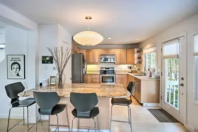 a kitchen with a large marble table and chairs at Lakefront Otis Home with Stunning Views and Boats! in Otis