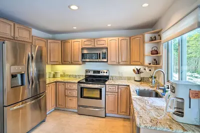 a kitchen with wooden cabinets and stainless steel appliances at Lakefront Otis Home with Stunning Views and Boats! in Otis