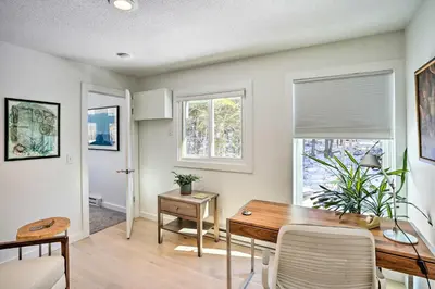 a dining room with a table and two windows at Lakefront Otis Home with Stunning Views and Boats! in Otis