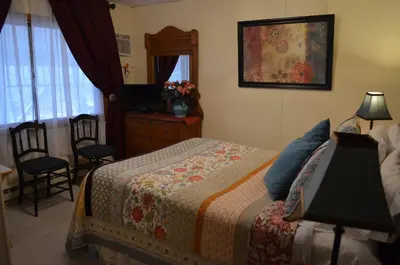 a bedroom with a bed and a dresser and a mirror at The Bavarian Manor Hotel in Purling