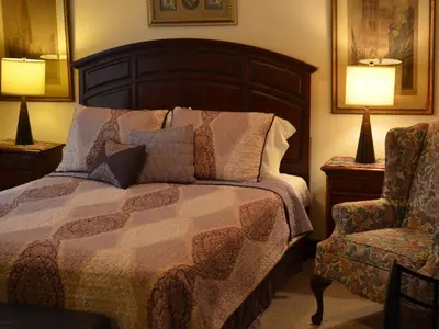 a bedroom with a bed and a chair and two lamps at The Bavarian Manor Hotel in Purling