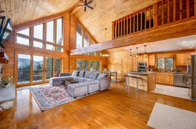 a living room with a couch and a kitchen at Beautiful Chalet, mins to Hunter/Windham slopes in Jewett