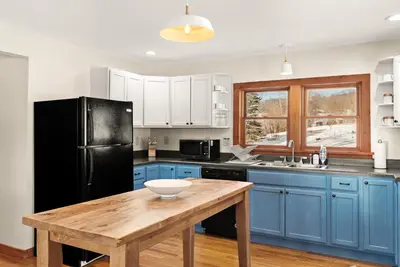 a kitchen with blue cabinets and a wooden table at Stella Firma in Bloomville