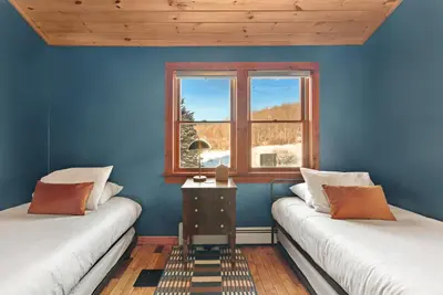 a blue room with two beds and a window at Stella Firma in Bloomville