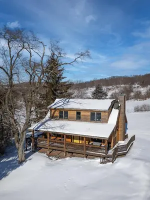 a log home with snow on the roof at Stella Firma in Bloomville