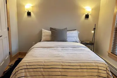 a bed in a bedroom with two lights on the wall at Hÿgge House in Margaretville