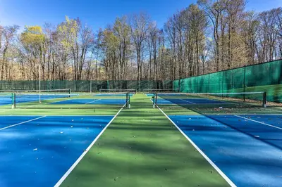 two tennis courts with trees in the background at Pet-Friendly Home with Deck at Big Bass Lake! in Gouldsboro