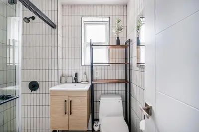 a bathroom with a toilet and a sink and a window at 39-2 Renovated 3BR Prime Hudson Yards Area in New York