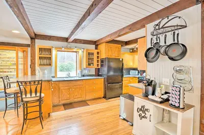 a kitchen with wooden cabinets and a table and chairs at Berkshires Getaway Less Than 1 Mi Skiing and Hiking! in Shelburne Falls