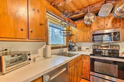 a kitchen with wooden cabinets and a sink at West Cornwall Cabin about 4 Mi to Covered Bridge! in West Cornwall