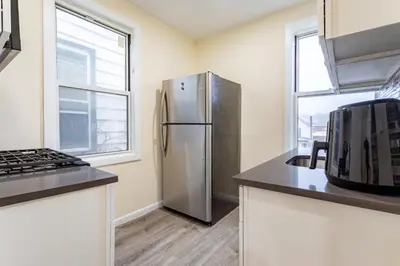 a kitchen with a stainless steel refrigerator and a window at Luxe Retreat 2 Bedroom Hideaway Minutes from NYC in New Rochelle