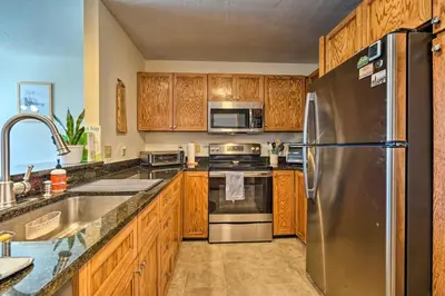 a kitchen with wooden cabinets and stainless steel appliances at Idyllic Mount Snow Condo with View and Amenities! in West Dover