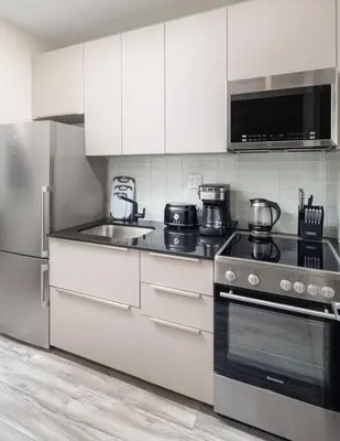 a kitchen with stainless steel appliances and white cabinets at Modern Spacious Apartment in Chelsea in New York