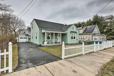 a green house with a white fence in front of it at Bridgeport Vacation Rental - Walk to Beach! in Bridgeport