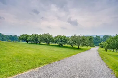 a gravel road leading through a field with trees at Vacation Rental Home in the Berkshires! in Williamstown