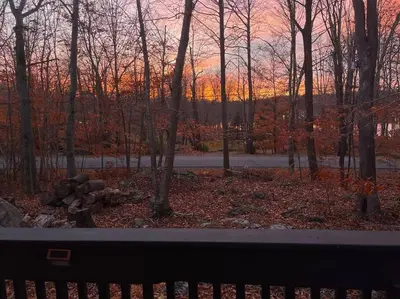 a view of a sunset from a window with trees at Stylish and Cozy Cabin, Walking Distance to Big Bass Lake in Gouldsboro