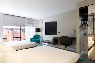 a hotel room with two beds and a desk and a television at Renaissance New York Harlem Hotel in New York