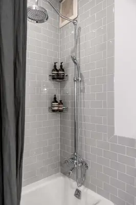 a bathroom with a shower with a white tub at Tribeca Loft Vanderbilt by RoveTravel in New York