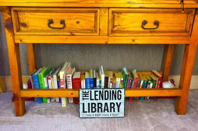 a book shelf filled with books under a desk at Wine Moose w Hot tub Fireplace Sauna 9min to Mt Snow in Dover