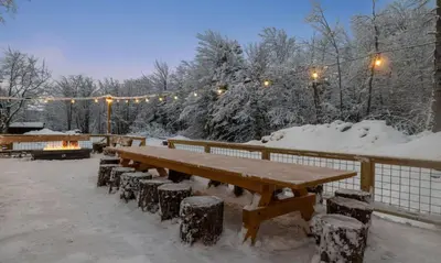 a wooden picnic table in the snow with lights at Maple Pine w Hot Tub Pool Table 3min to Mount Snow in Dover