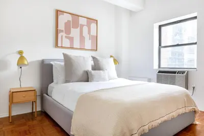 a white bedroom with a large bed and a window at Chelsea 1BR w Gym nr Penn Station MSG NYC-528 in New York