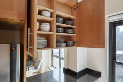 a kitchen with wooden cabinets and plates on shelves at Midtown E 2BR w WD nr Central Park NYC-531 in New York