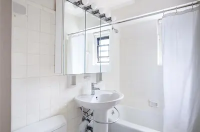 a white bathroom with a sink and a bath tub at Midtown E 2BR w WD nr Central Park NYC-531 in New York