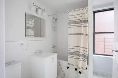 a white bathroom with a sink and a shower curtain at UWS 2br w elevator doorman gym nr Central Park NYC-952 in New York