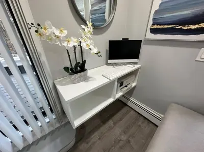 a white desk with a computer and flowers on it at Luxury 3Bed Private Apartment Near Manhattan in New Rochelle