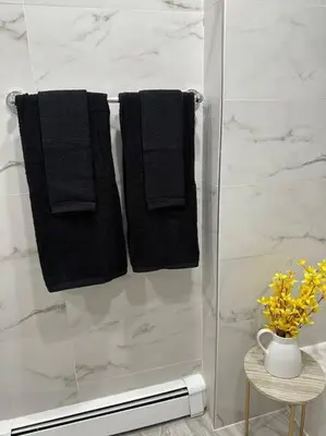 a shower with two black towels and a vase of flowers at Luxury 3Bed Private Apartment Near Manhattan in New Rochelle