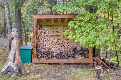 a pile of fire wood next to a wooden shed at Accord Vacation Rental with Pool and Hot Tub! in Accord