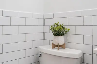 a white tiled bathroom with a toilet with a plant on it at 74-4A 2BR 2baths in Prime Upper West Side w d GYM in New York