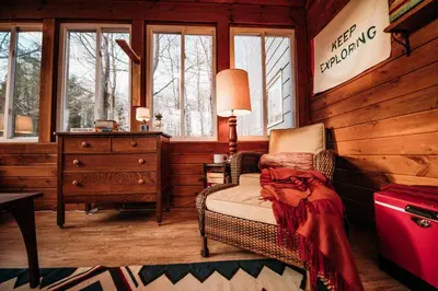 a room with a chair and a dresser and windows at Hot Cocoa Bar 4 Season Porch wWood Stove in Pocono Country Place