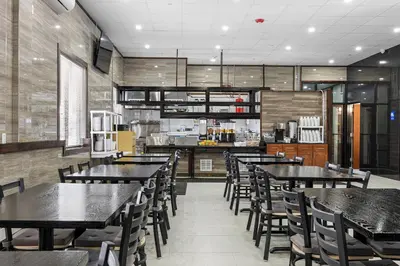 a restaurant with tables and chairs and a kitchen at Highbridge Hotel in Bronx