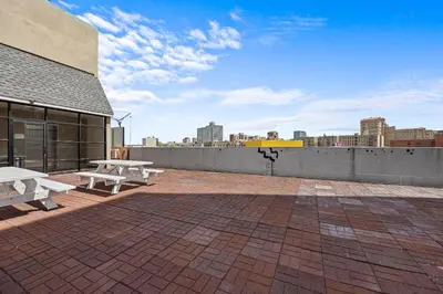 a patio with two picnic tables on top of a building at Highbridge Hotel in Bronx