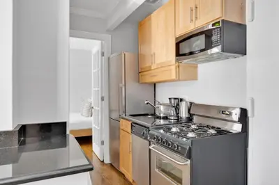 a kitchen with stainless steel appliances and wooden cabinets at E Village 1BR w in-unit WD nr Park NYC-722 in New York