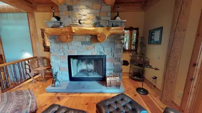 a living room with a stone fireplace in a house at Cayuga Lodge South in Cooperstown