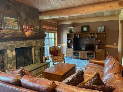 a living room with leather furniture and a stone fireplace at Seneca Lodge in Cooperstown