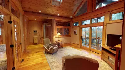 a large living room with wooden ceilings and a television at Seneca Lodge in Cooperstown