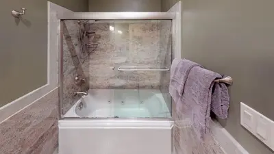 a bathroom with a bath tub with a glass door at Seneca Lodge in Cooperstown