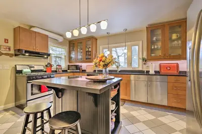 a kitchen with wooden cabinets and a island with bar stools at Hadley Vacation Rental 24 Mi to Springfield! in Hadley