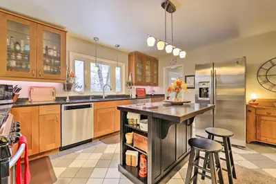 a kitchen with wooden cabinets and a island with bar stools at Hadley Vacation Rental 24 Mi to Springfield! in Hadley