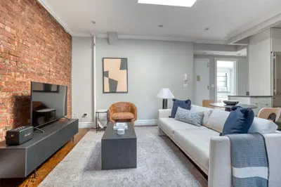 a living room with a couch and a brick wall at UES 3br penthouse w wd nr Central Park NYC-1110 in New York
