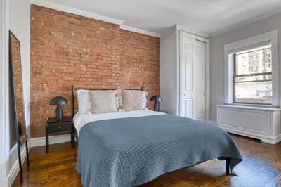 a bedroom with a brick wall and a bed at UES 3br penthouse w wd nr Central Park NYC-1110 in New York