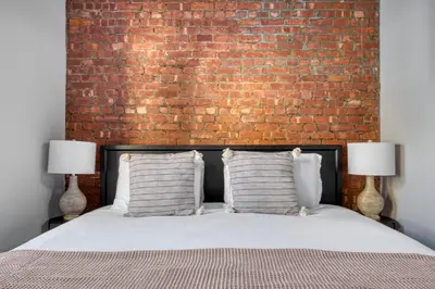 a bedroom with a brick wall and a bed with two lamps at UES 3br penthouse w wd nr Central Park NYC-1110 in New York