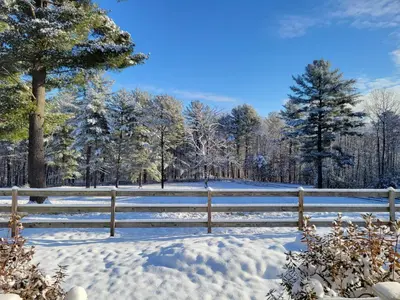 a fence covered in snow with trees in the background at The Suite at Liberty Woods in Belchertown