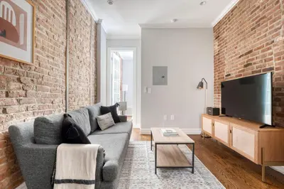 a living room with a couch and a brick wall at East Village 1br w wd nr cafes NYC-1115 in New York